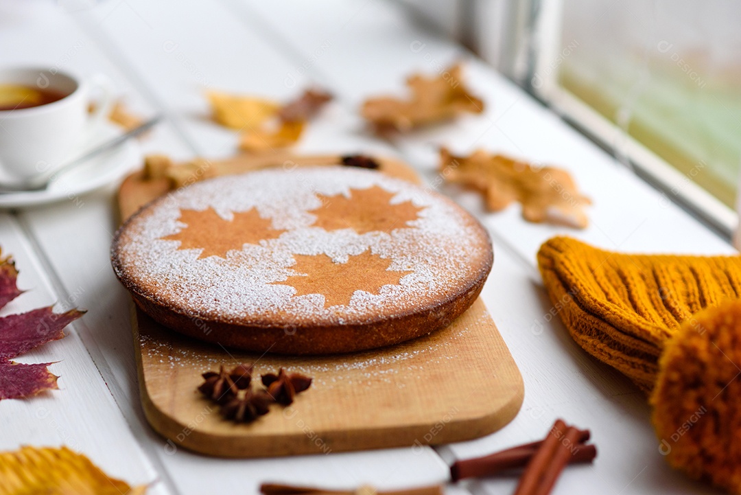 Lindo bolo de abóbora doce fresco com um padrão de folha de bordo sobre um fundo branco de madeira com uma composição de folhas secas de outono
