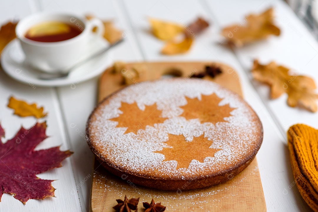 Lindo bolo de abóbora doce fresco com um padrão de folha de bordo sobre um fundo branco de madeira com uma composição de folhas secas de outono