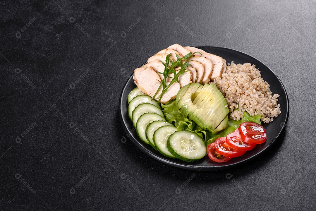 Salada deliciosa fresca com quinoa, frango e legumes frescos num prato sobre um fundo escuro de concreto