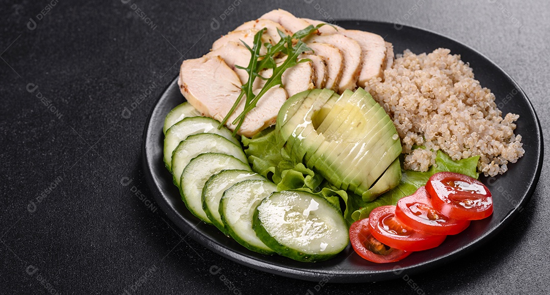 Salada deliciosa fresca com quinoa, frango e legumes frescos num prato sobre um fundo escuro de concreto