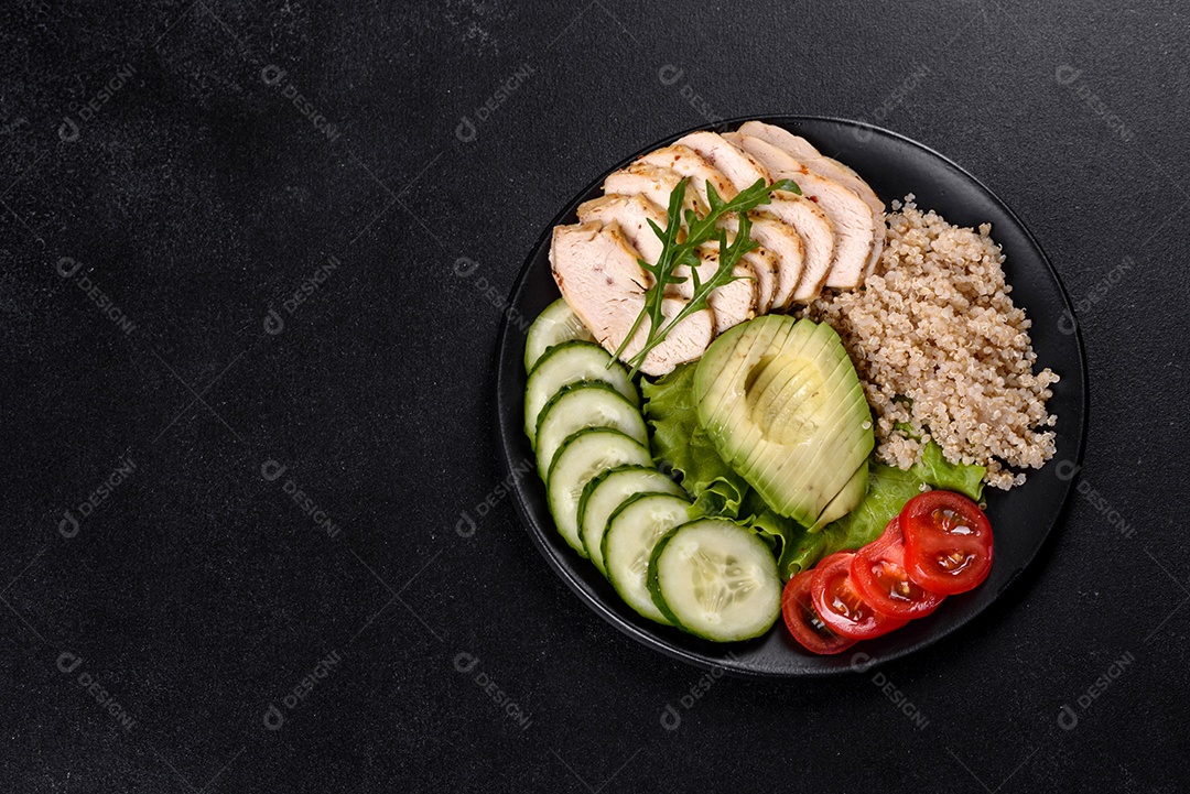 Salada deliciosa fresca com quinoa, frango e legumes frescos num prato sobre um fundo escuro de concreto