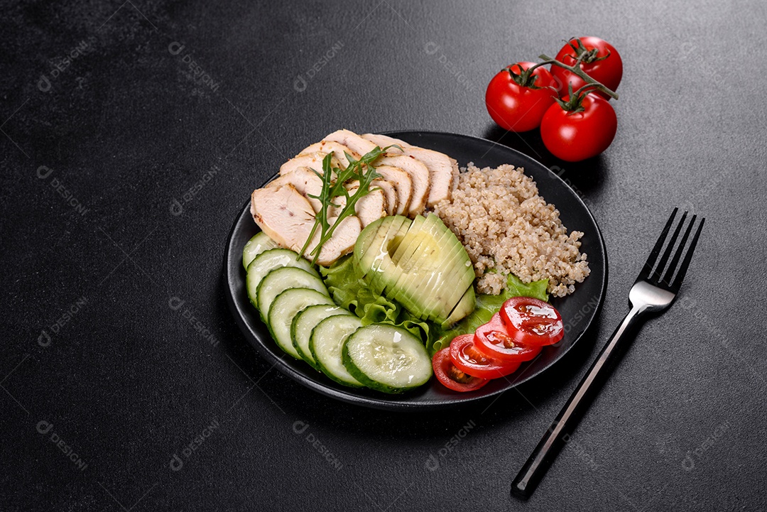 Salada deliciosa fresca com quinoa, frango e legumes frescos num prato sobre um fundo escuro de concreto