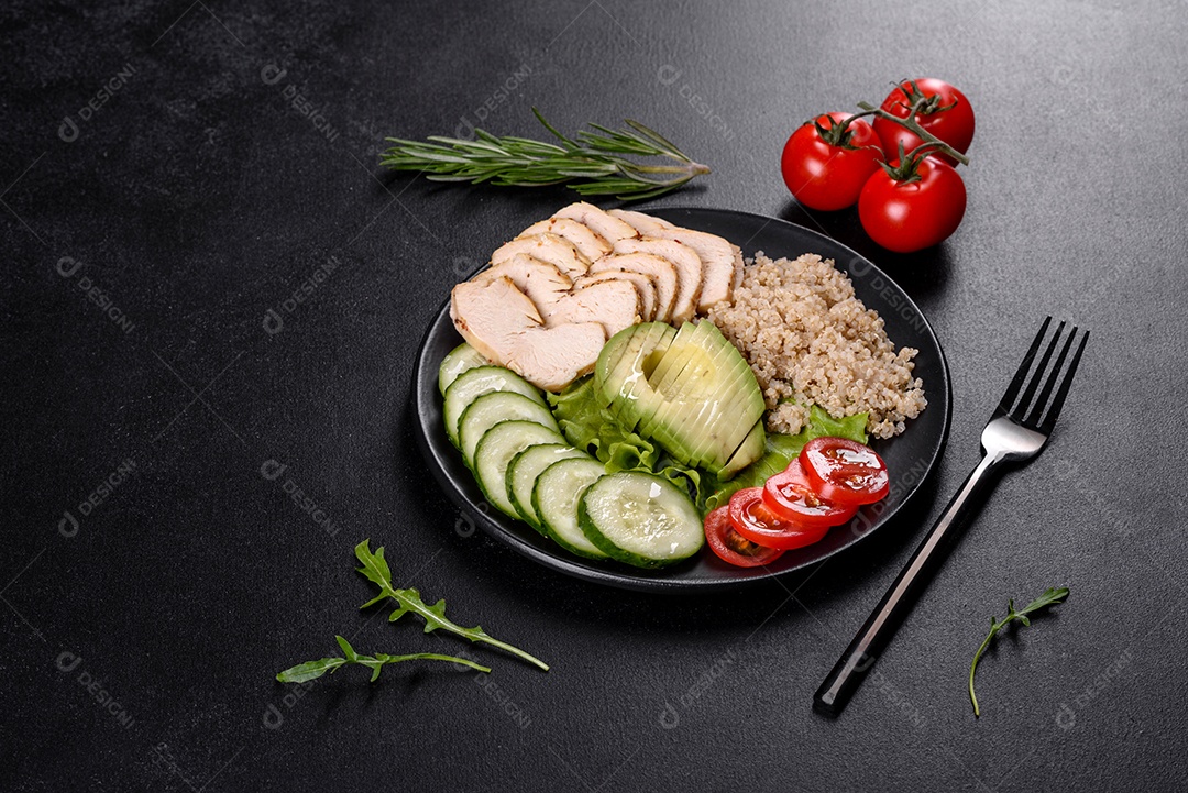 Salada deliciosa fresca com quinoa, frango e legumes frescos num prato sobre um fundo escuro de concreto
