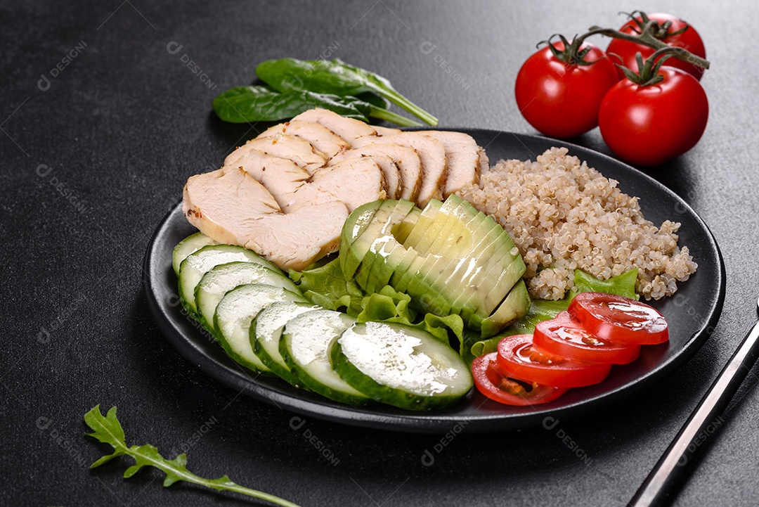 Salada deliciosa fresca com quinoa, frango e legumes frescos num prato sobre um fundo escuro de concreto