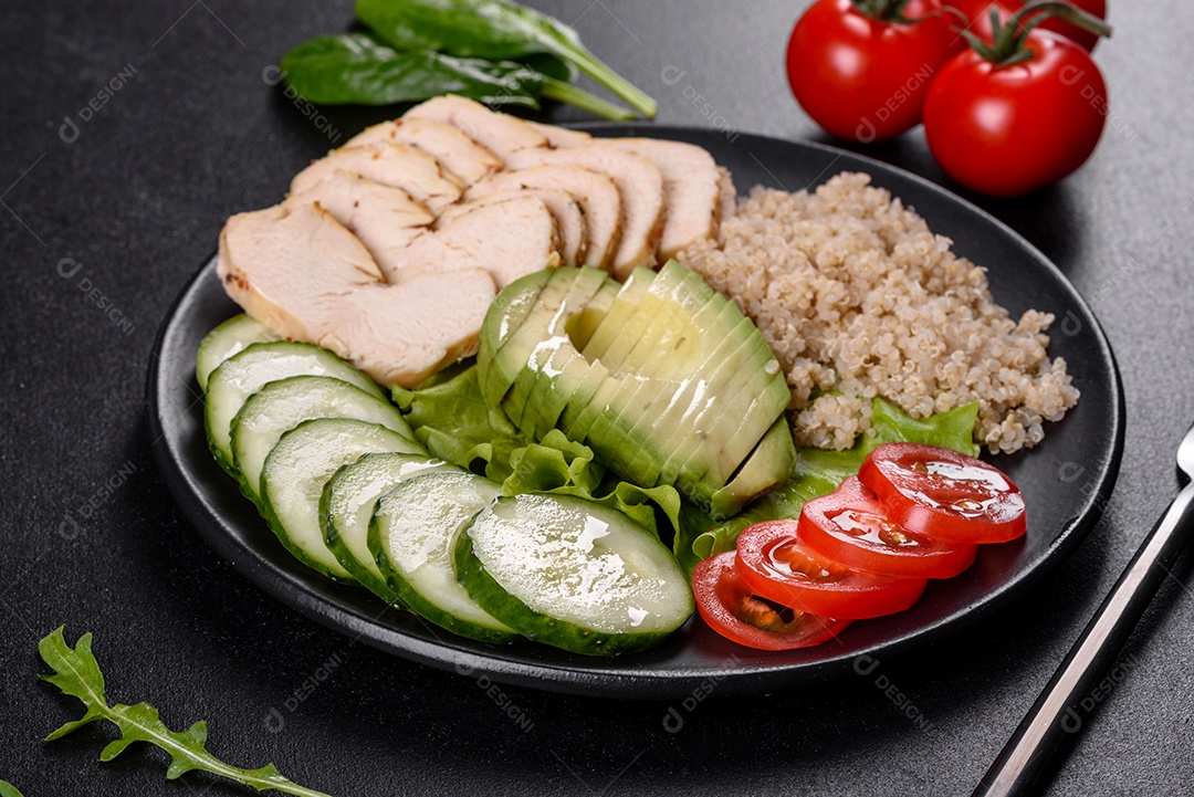 Salada deliciosa fresca com quinoa, frango e legumes frescos num prato sobre um fundo escuro de concreto