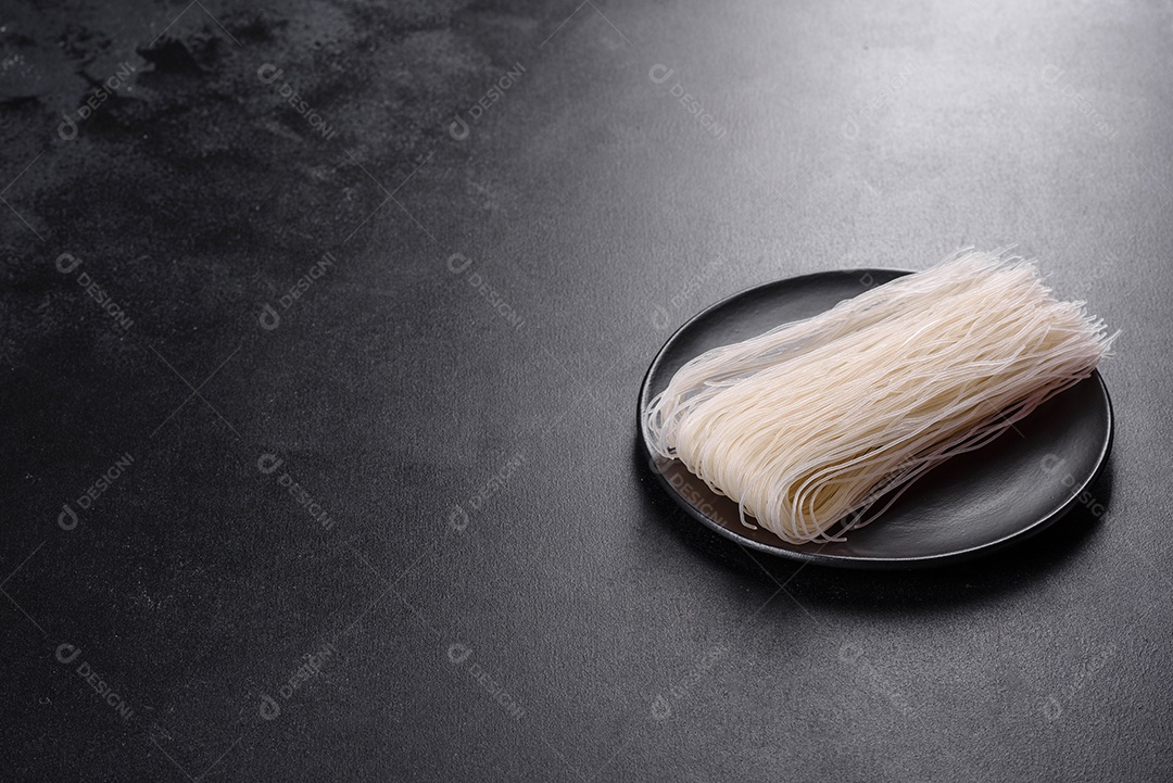Macarrão de arroz saboroso com tomate, pimenta vermelha, cogumelos e frutos do mar em um fundo escuro de concreto