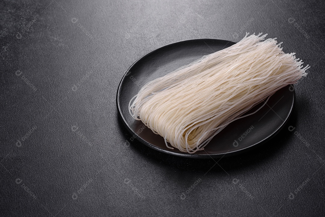 Macarrão de arroz saboroso com tomate, pimenta vermelha, cogumelos e frutos do mar em um fundo escuro de concreto