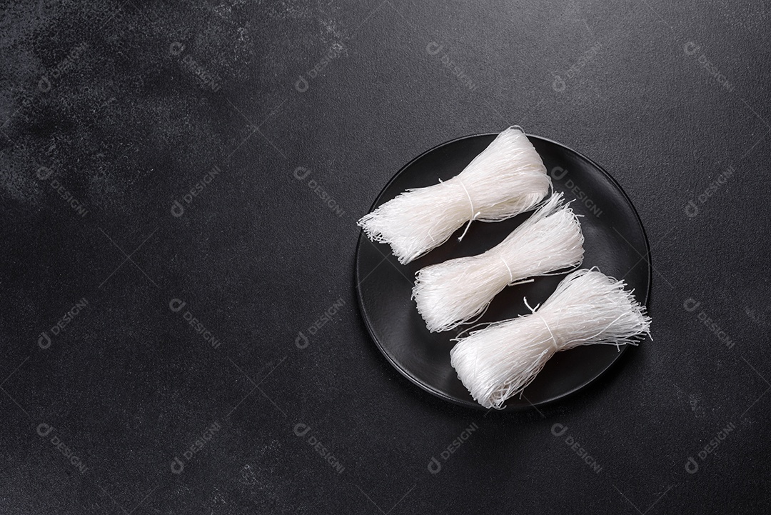 Macarrão de arroz saboroso com tomate, pimenta vermelha, cogumelos e frutos do mar em um fundo escuro de concreto