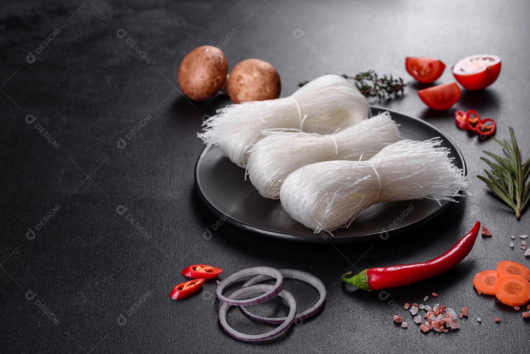 Macarrão de arroz saboroso com tomate, pimenta vermelha, cogumelos e frutos do mar em um fundo escuro de concreto