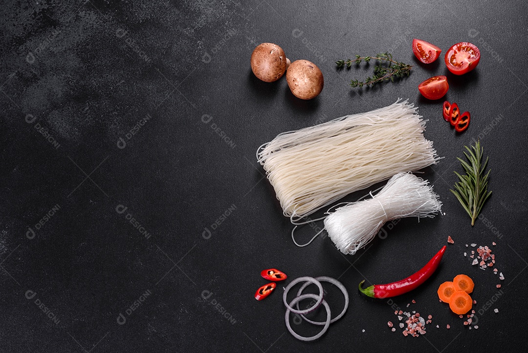 Macarrão de arroz saboroso com tomate, pimenta vermelha, cogumelos e frutos do mar em um fundo escuro de concreto
