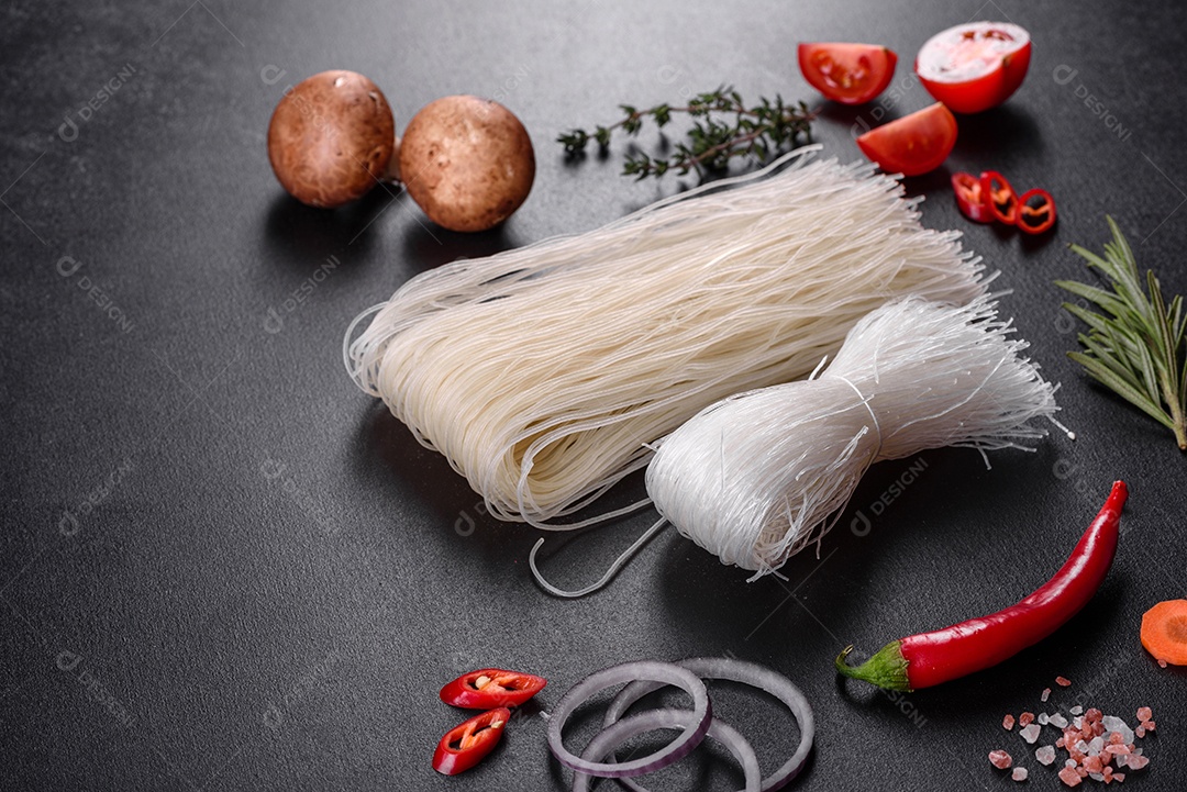Macarrão de arroz saboroso com tomate, pimenta vermelha, cogumelos e frutos do mar em um fundo escuro de concreto