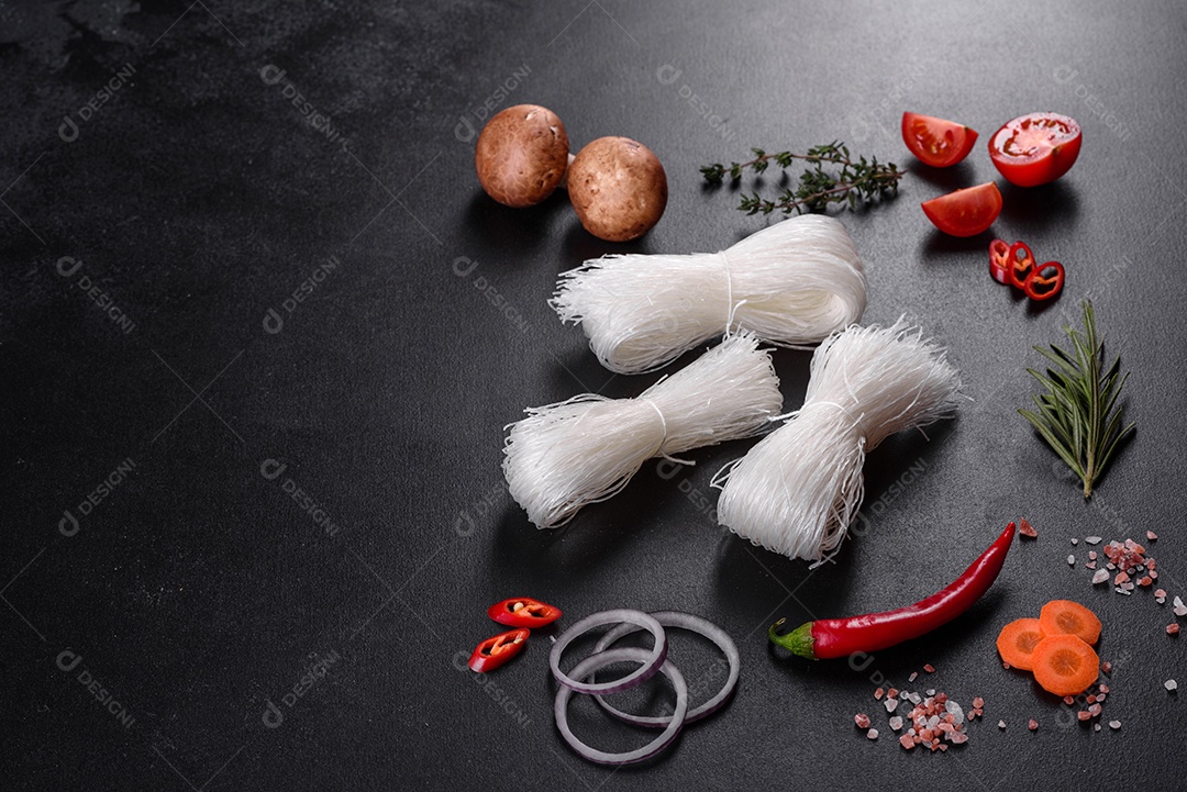 Macarrão de arroz saboroso com tomate, pimenta vermelha, cogumelos e frutos do mar em um fundo escuro de concreto