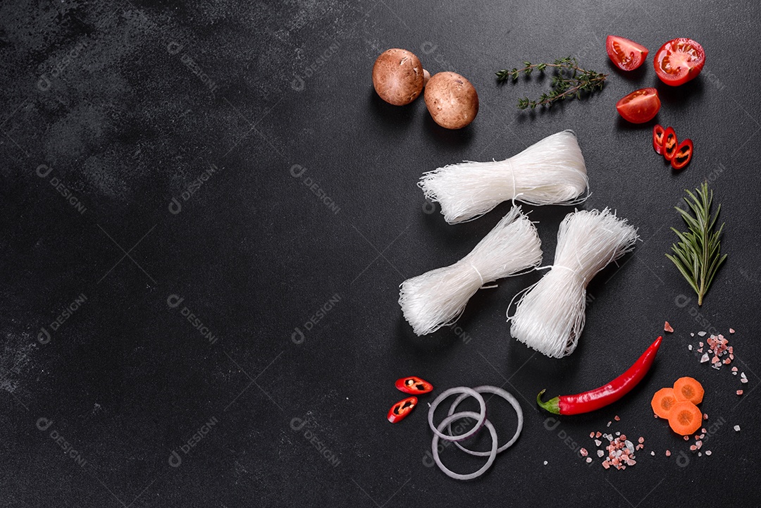 Macarrão de arroz saboroso com tomate, pimenta vermelha, cogumelos e frutos do mar em um fundo escuro de concreto