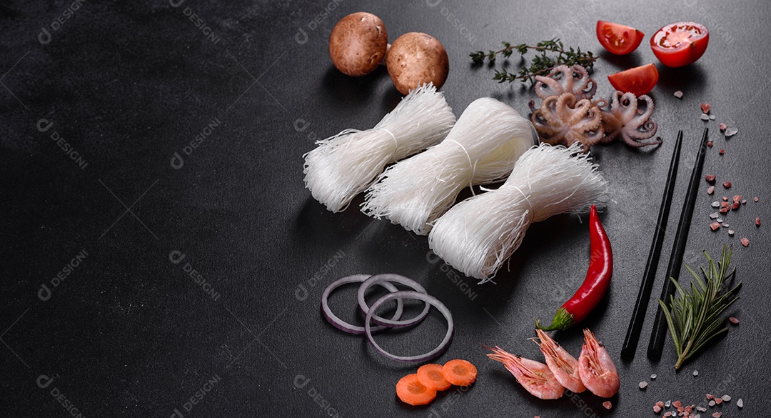 Macarrão de arroz saboroso com tomate, pimenta vermelha, cogumelos e frutos do mar em um fundo escuro de concreto