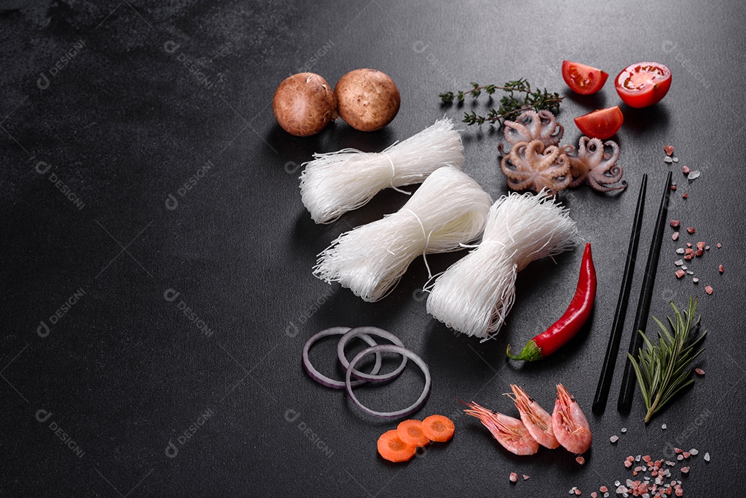 Macarrão de arroz saboroso com tomate, pimenta vermelha, cogumelos e frutos do mar em um fundo escuro de concreto