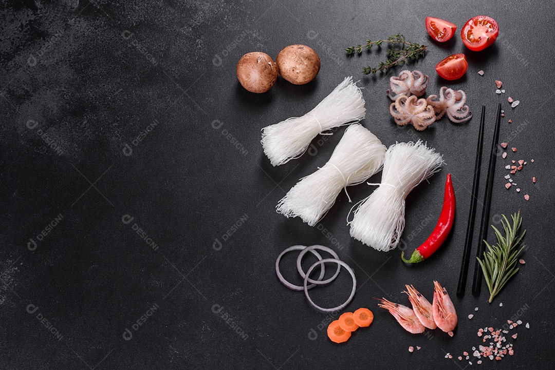 Macarrão de arroz saboroso com tomate, pimenta vermelha, cogumelos e frutos do mar em um fundo escuro de concreto