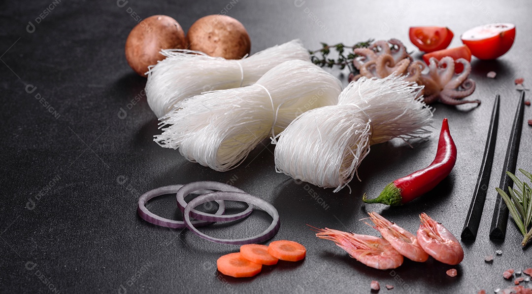 Macarrão de arroz saboroso com tomate, pimenta vermelha, cogumelos e frutos do mar em um fundo escuro de concreto