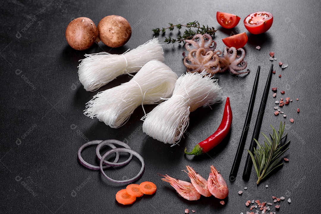 Macarrão de arroz saboroso com tomate, pimenta vermelha, cogumelos e frutos do mar em um fundo escuro de concreto