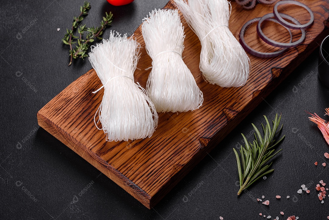 Macarrão de arroz saboroso com tomate, pimenta vermelha, cogumelos e frutos do mar em um fundo escuro de concreto