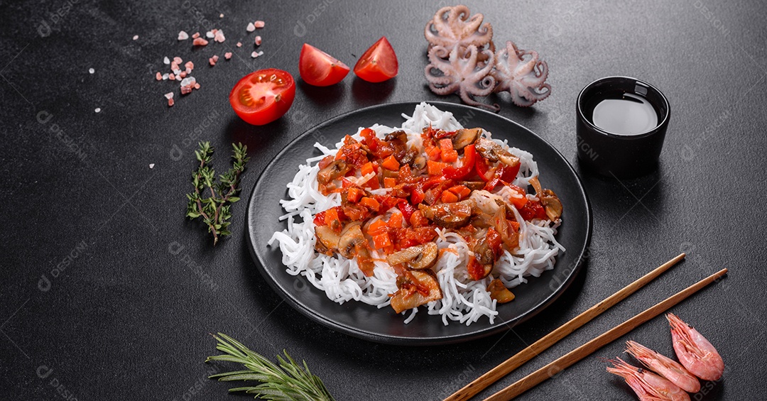 Macarrão de arroz saboroso com tomate, pimenta vermelha, cogumelos e frutos do mar em um fundo escuro de concreto