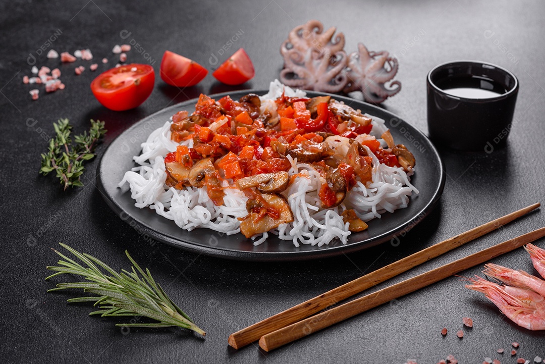 Macarrão de arroz saboroso com tomate, pimenta vermelha, cogumelos e frutos do mar em um fundo escuro de concreto