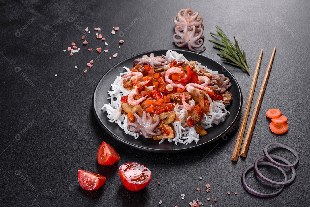 Macarrão de arroz saboroso com tomate, pimenta vermelha, cogumelos e frutos do mar em um fundo escuro de concreto