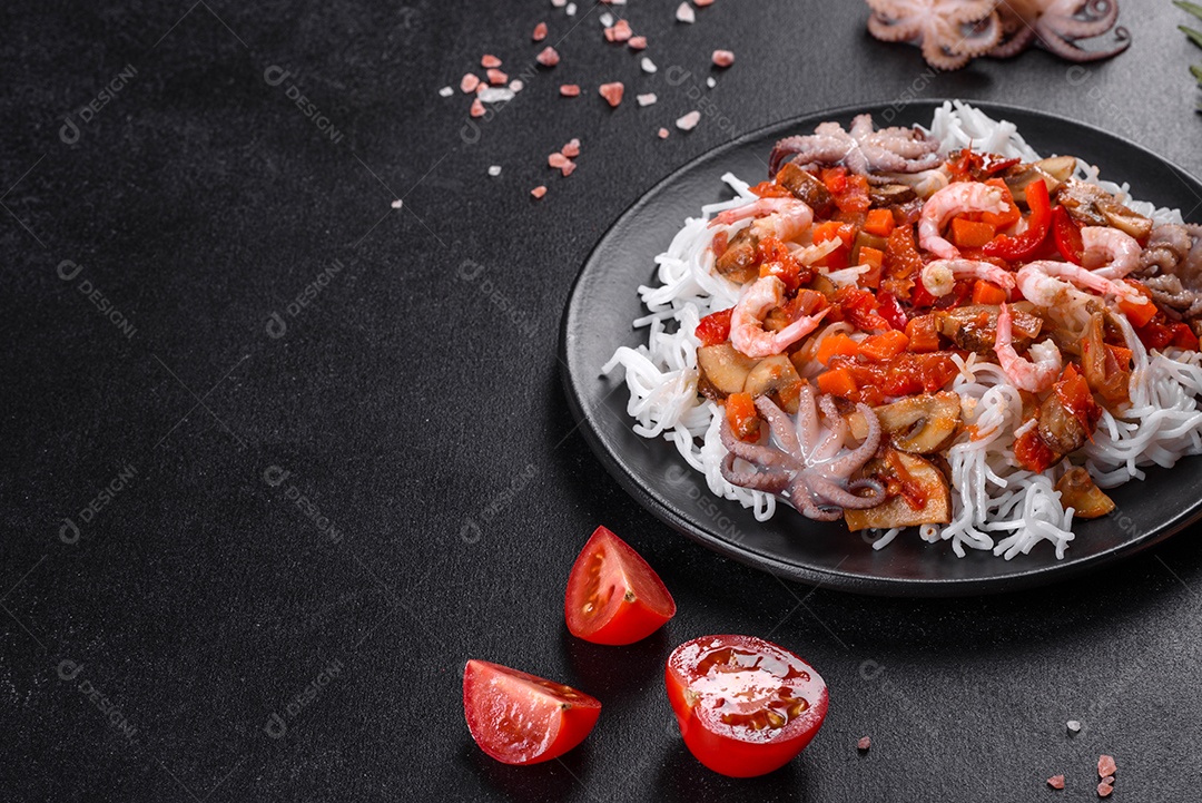 Macarrão de arroz saboroso com tomate, pimenta vermelha, cogumelos e frutos do mar em um fundo escuro de concreto