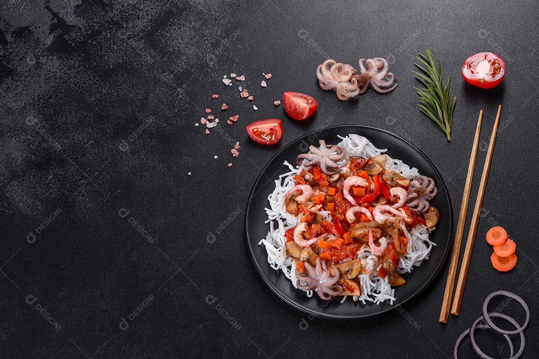 Macarrão de arroz saboroso com tomate, pimenta vermelha, cogumelos e frutos do mar em um fundo escuro de concreto