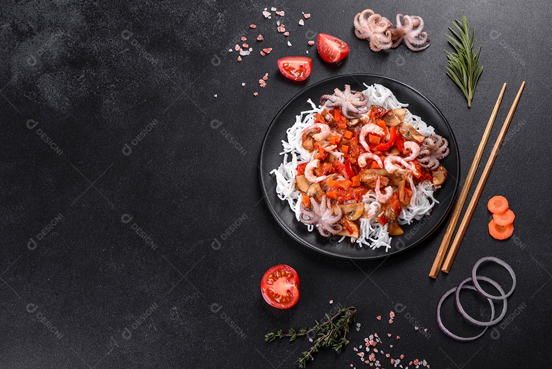 Macarrão de arroz saboroso com tomate, pimenta vermelha, cogumelos e frutos do mar em um fundo escuro de concreto