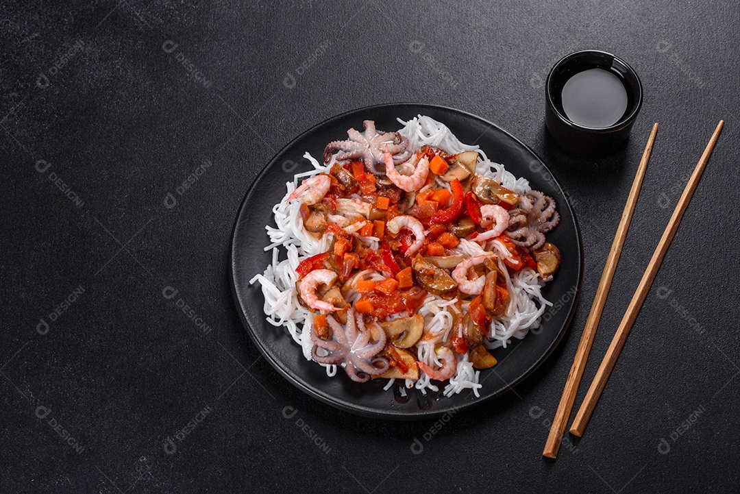 Macarrão de arroz saboroso com tomate, pimenta vermelha, cogumelos e frutos do mar em um fundo escuro de concreto