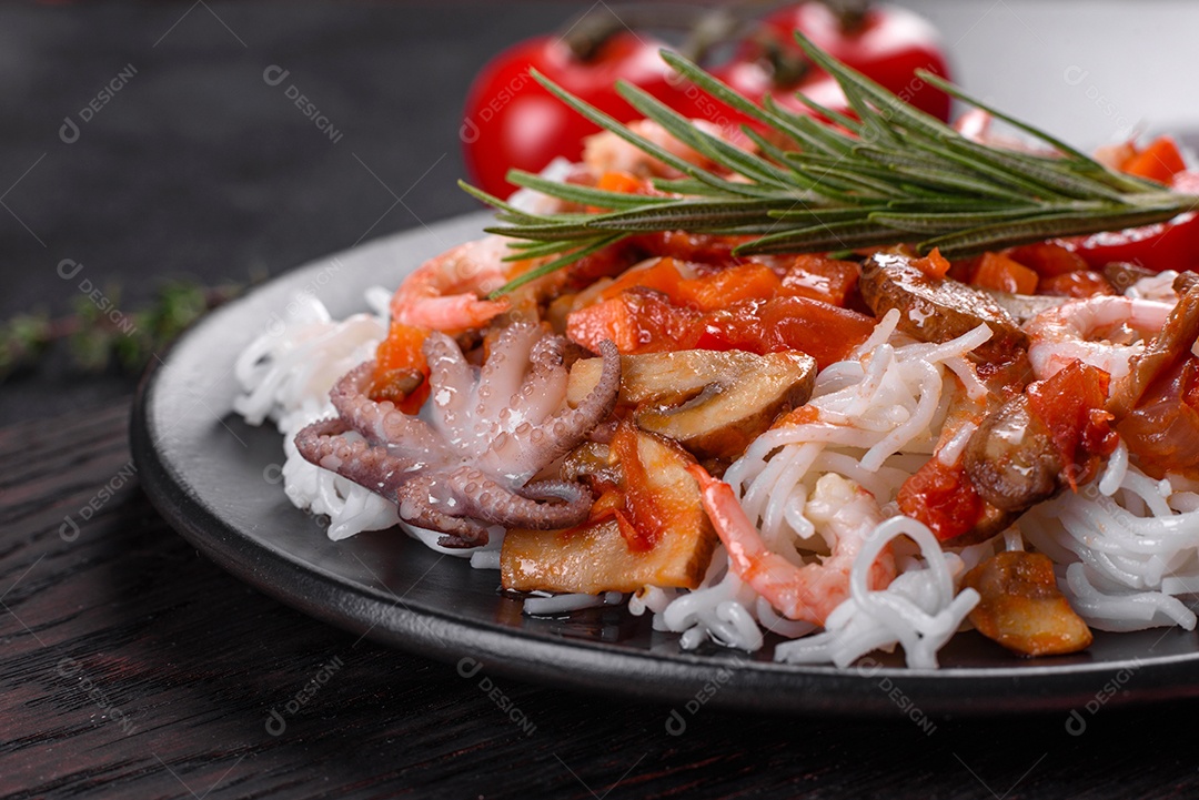 Macarrão de arroz saboroso com tomate, pimenta vermelha, cogumelos e frutos do mar em um fundo escuro de concreto