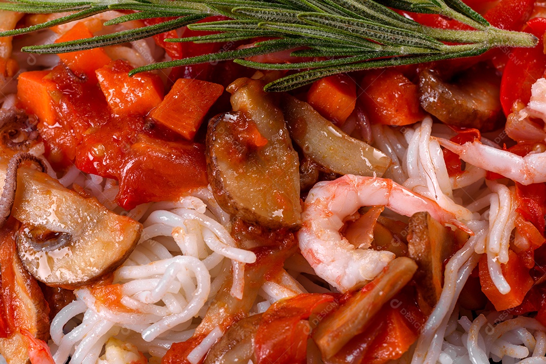 Macarrão de arroz saboroso com tomate, pimenta vermelha, cogumelos e frutos do mar em um fundo escuro de concreto