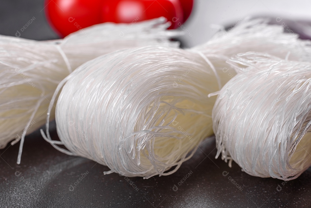 Macarrão de arroz saboroso com tomate, pimenta vermelha, cogumelos e frutos do mar em um fundo escuro de concreto