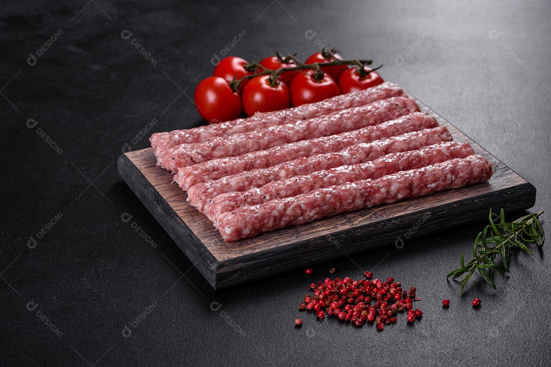 Salsichas de porco cruas frescas com especiarias numa tábua de madeira sobre uma mesa de concreto escuro