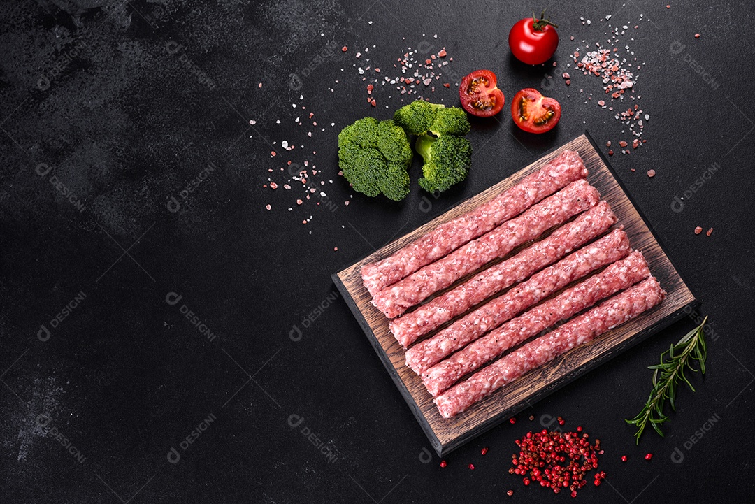 Salsichas de porco cruas frescas com especiarias numa tábua de madeira sobre uma mesa de concreto escuro