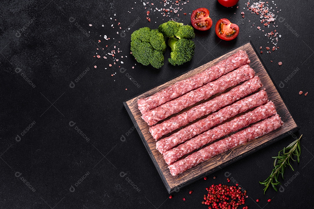 Salsichas de porco cruas frescas com especiarias numa tábua de madeira sobre uma mesa de concreto escuro