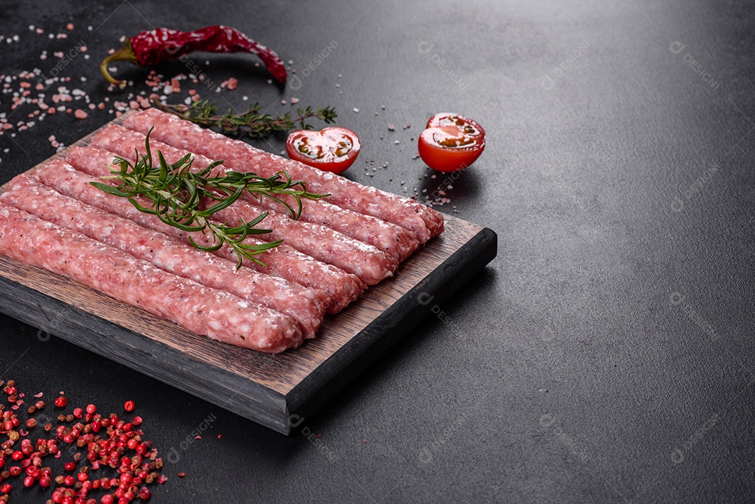 Salsichas de porco cruas frescas com especiarias numa tábua de madeira sobre uma mesa de concreto escuro