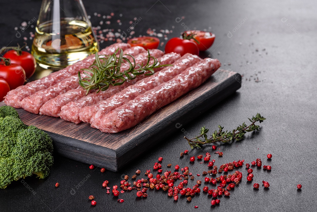 Salsichas de porco cruas frescas com especiarias numa tábua de madeira sobre uma mesa de concreto escuro