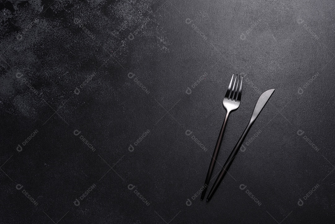 Talheres pretos sobre uma mesa escura de concreto. Preparação da mesa de jantar