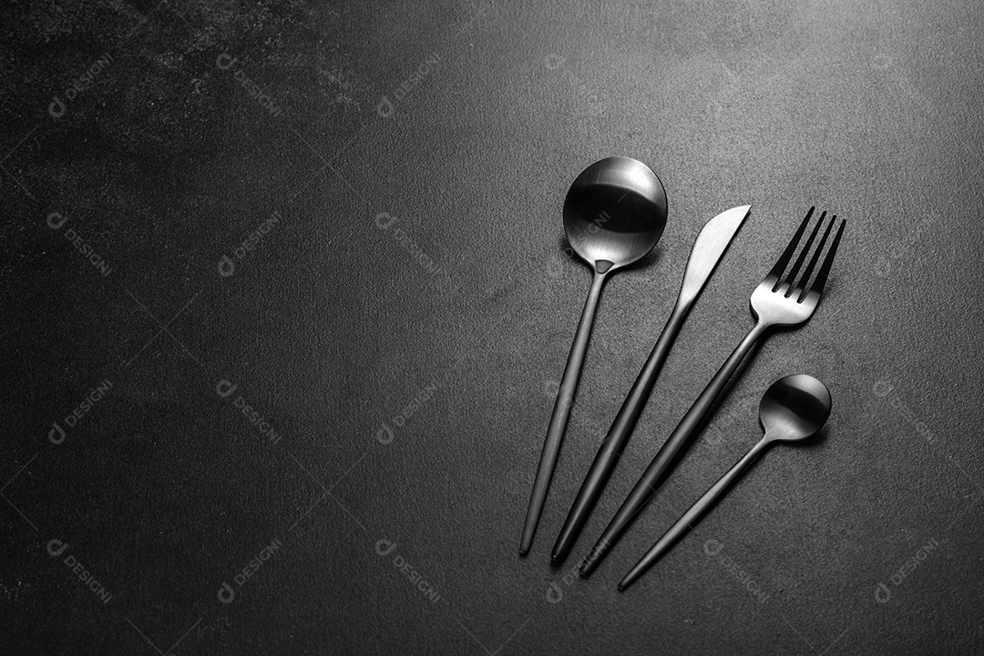 Talheres pretos sobre uma mesa escura de concreto. Preparação da mesa de jantar
