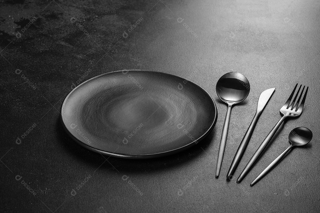 Talheres pretos sobre uma mesa escura de concreto. Preparação da mesa de jantar