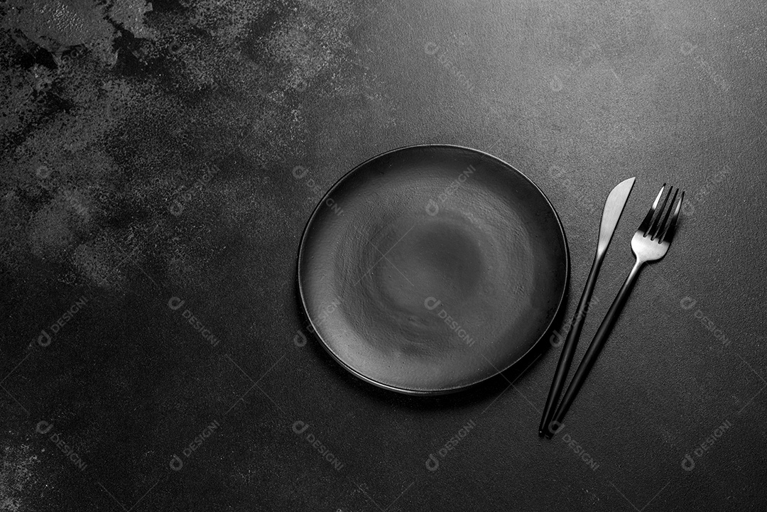 Talheres pretos sobre uma mesa escura de concreto. Preparação da mesa de jantar