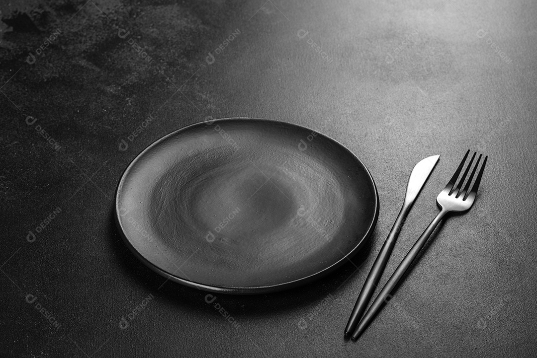 Talheres pretos sobre uma mesa escura de concreto. Preparação da mesa de jantar