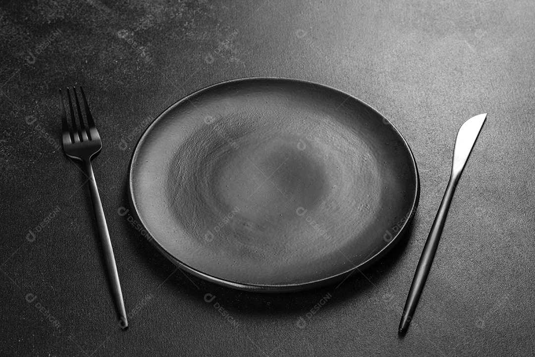 Talheres pretos sobre uma mesa escura de concreto. Preparação da mesa de jantar