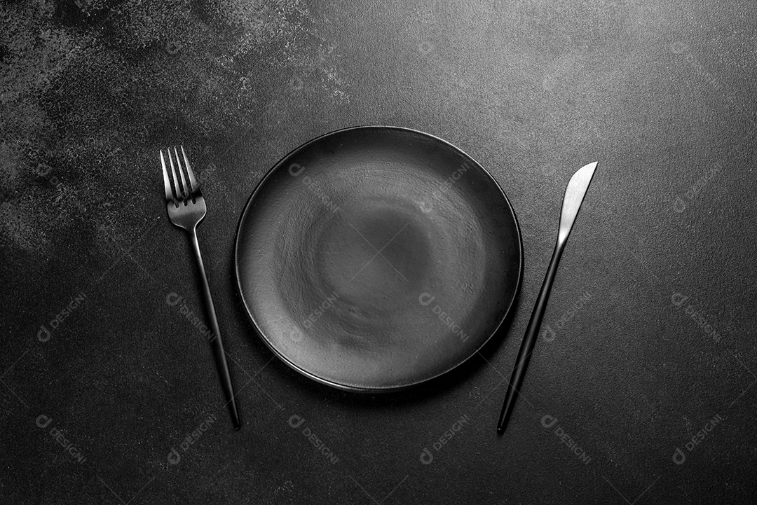 Talheres pretos sobre uma mesa escura de concreto. Preparação da mesa de jantar