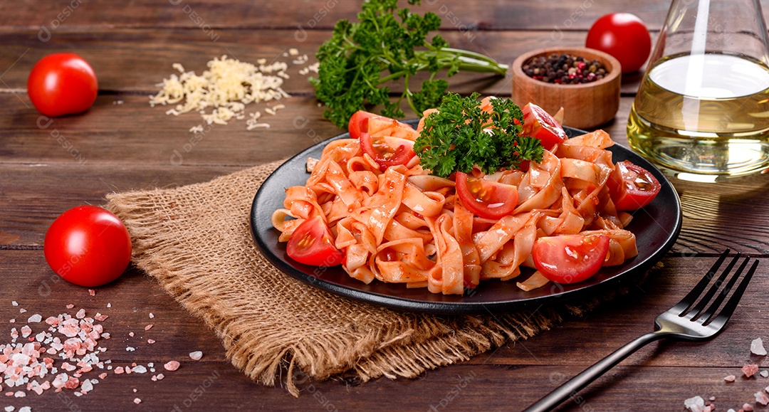 Deliciosa pasta fresca com molho de tomate com especiarias e ervas sobre fundo escuro. Cozinha mediterrânea