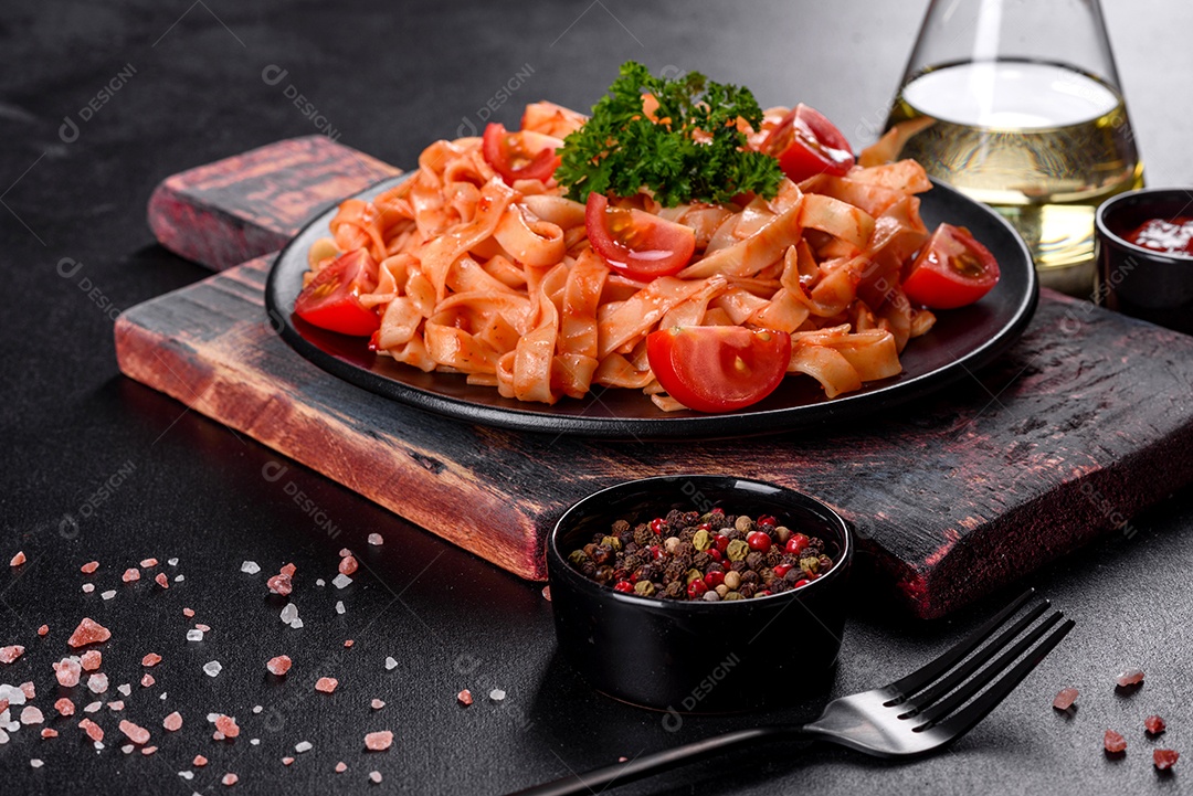Deliciosa pasta fresca com molho de tomate com especiarias e ervas sobre fundo escuro. Cozinha mediterrânea