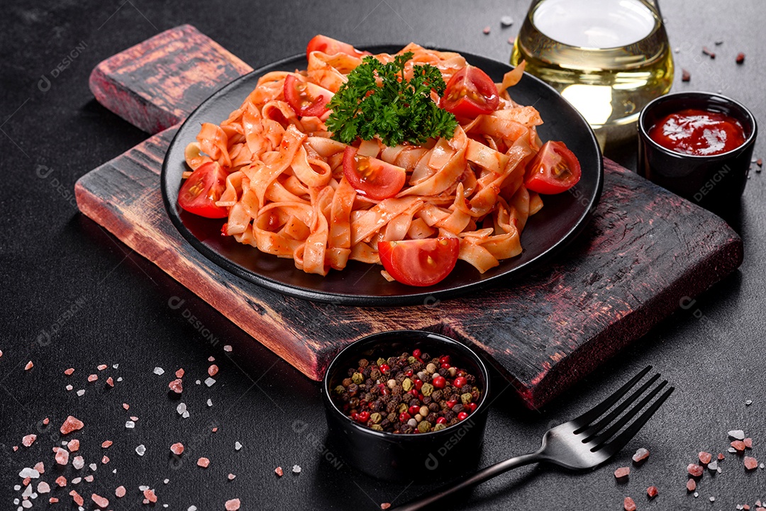 Deliciosa pasta fresca com molho de tomate com especiarias e ervas sobre fundo escuro. Cozinha mediterrânea