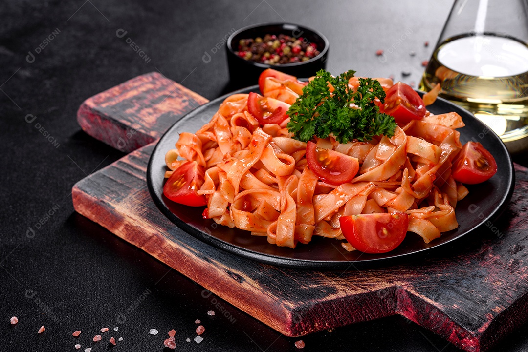 Deliciosa pasta fresca com molho de tomate com especiarias e ervas sobre fundo escuro. Cozinha mediterrânea