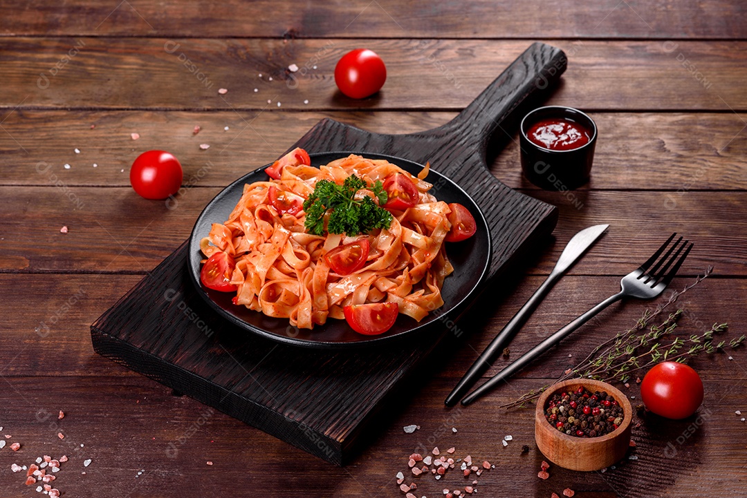 Deliciosa pasta fresca com molho de tomate com especiarias e ervas sobre fundo escuro. Cozinha mediterrânea